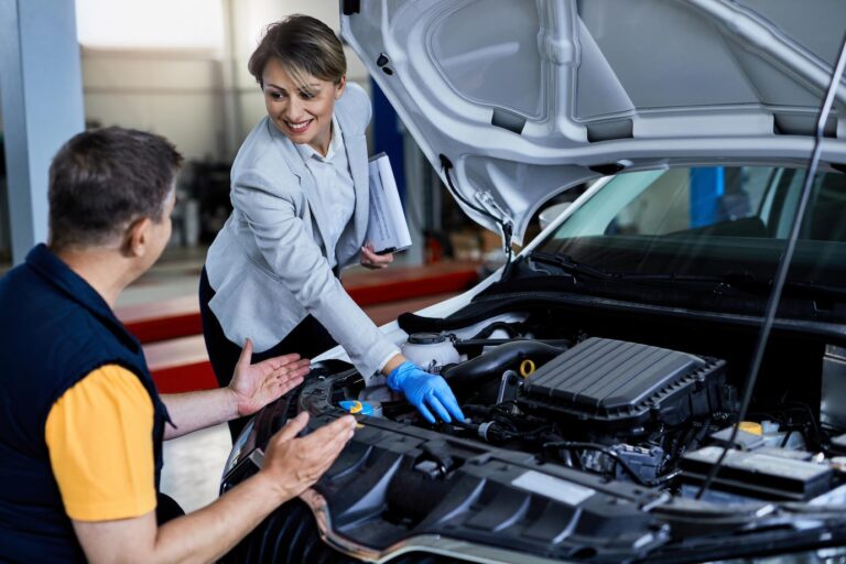 auto-mechanic-businesswoman-cooperating-while-checking-vehicle-hood-workshop_637285-7688